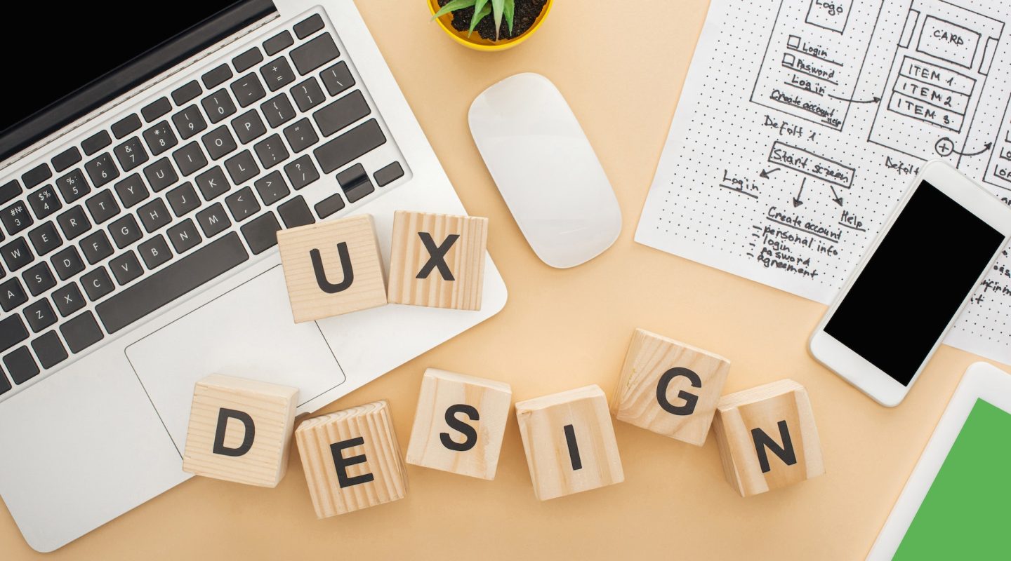 top view of gadgets near wooden blocks with ux design lettering website design template and green